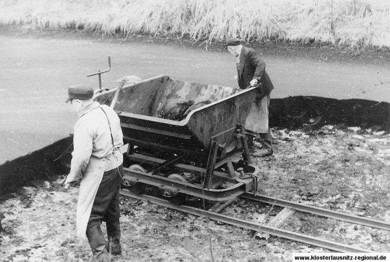 Die Kollegen Paul Haase und Wenzel Branke beladen Loren mit abgebadeter Masse, die wieder zurück auf die Moorwiesen gefahren wurde.